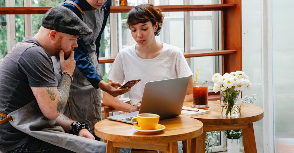 3 workers talking around a laptop.