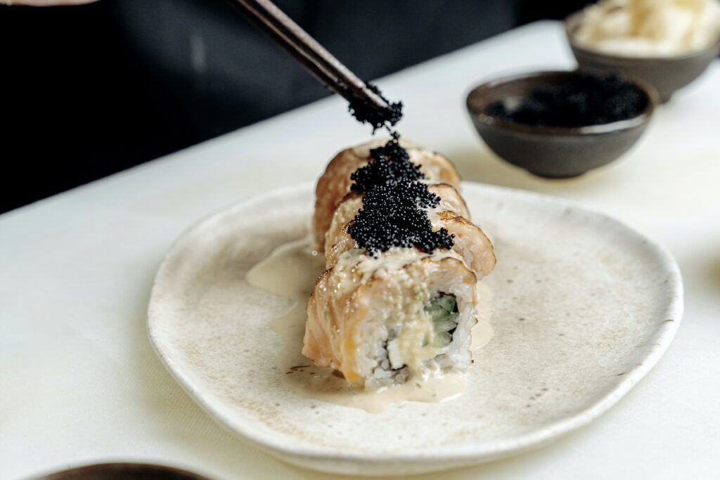 Chef placing caviar onto a sushi roll.