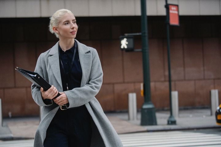 A woman holding a folder crossing the road.