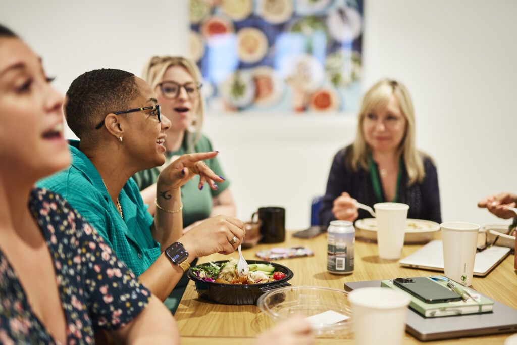 Coworkers sitting around a table and chatting during their lunch.