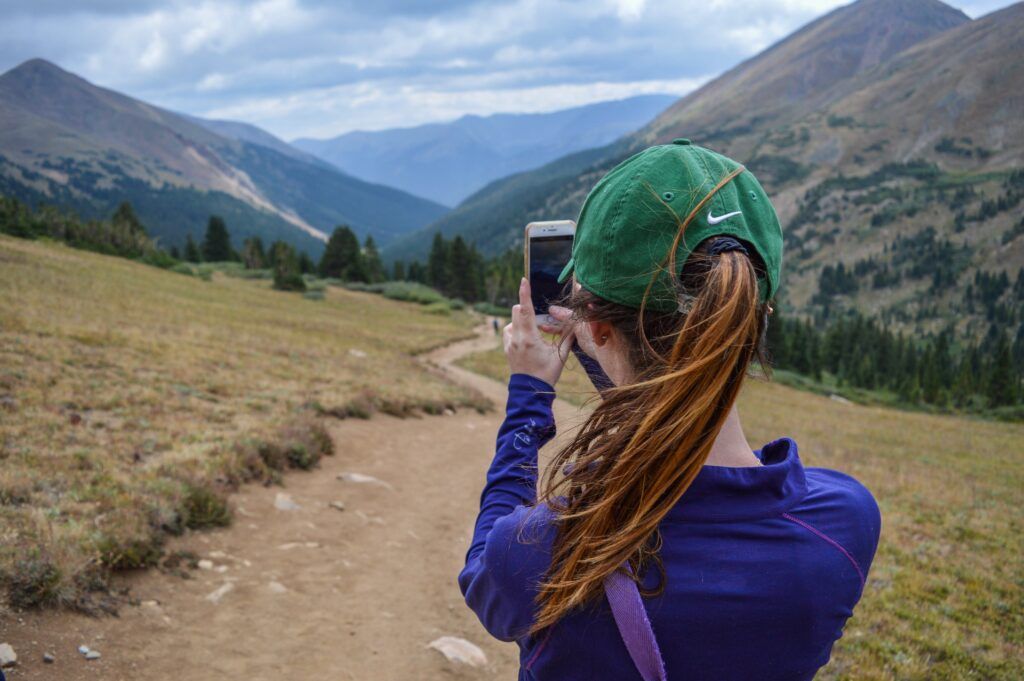 A woman taking a photo while on a hike.