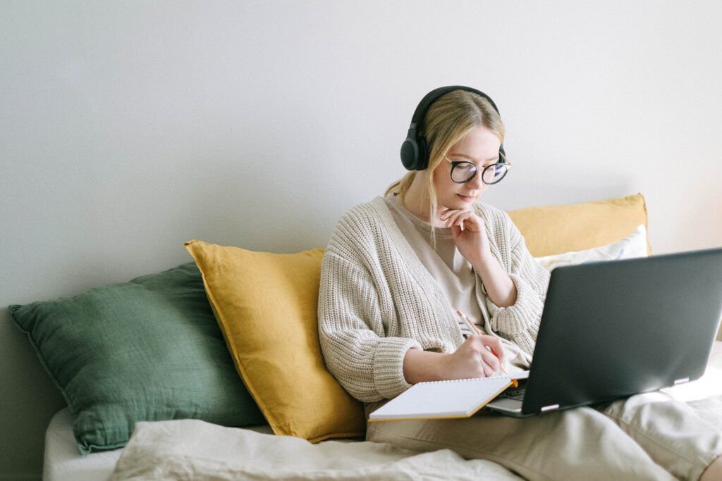 A woman sitting and listening to music through headphones while sitting on the couch.