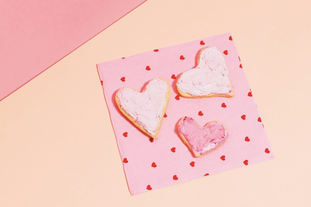 3 heart shaped cookies on a napkin with hearts. 