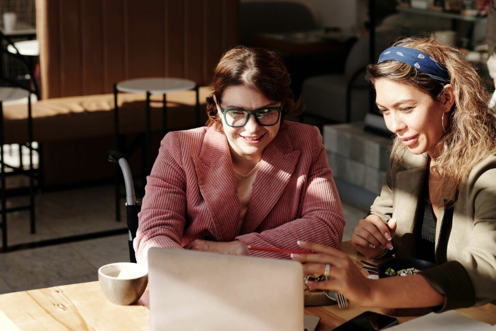 Two women at a restaurant sitting around a computer.