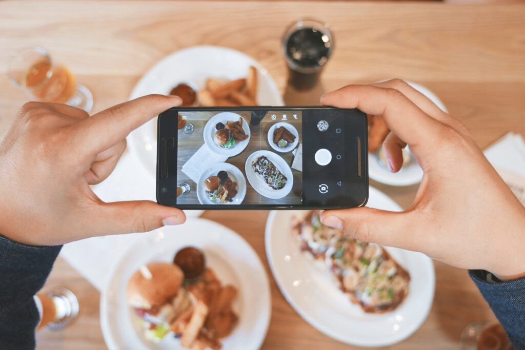 A person taking a photo of dishes of food. 
