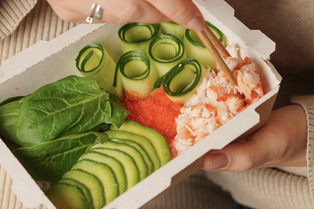 A woman eating a boxed lunch.